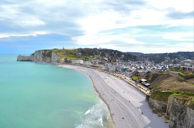 Étretat beach and town seen from the clifftop, with the pebble bay curving away towards the Amont cliff