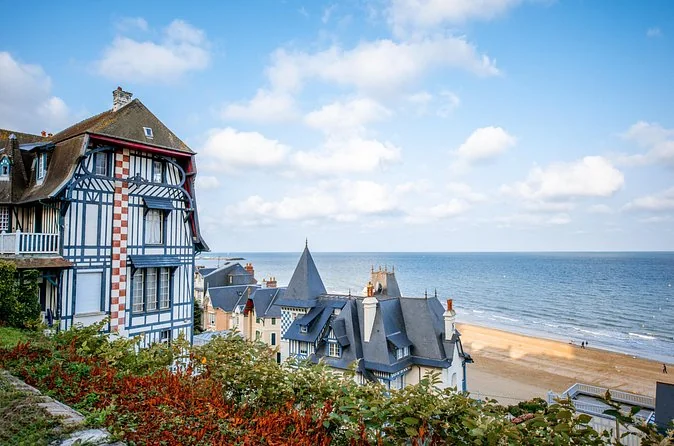 A turreted seaside villa above a sandy beach and blue sea at Trouville